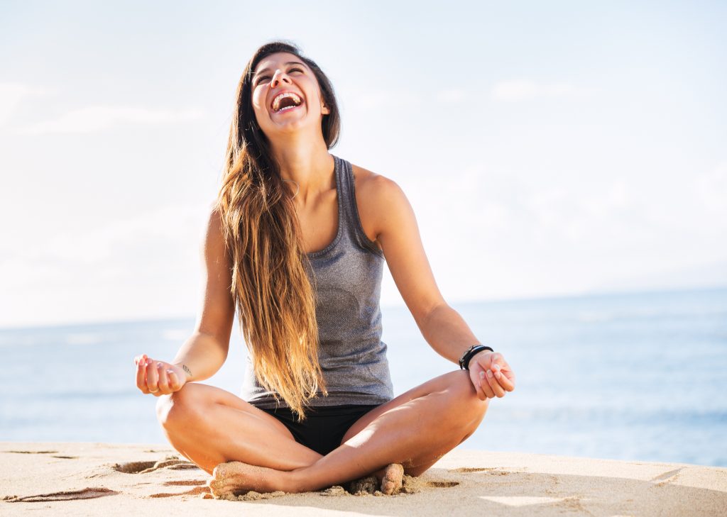 A woman meditating by the beach.