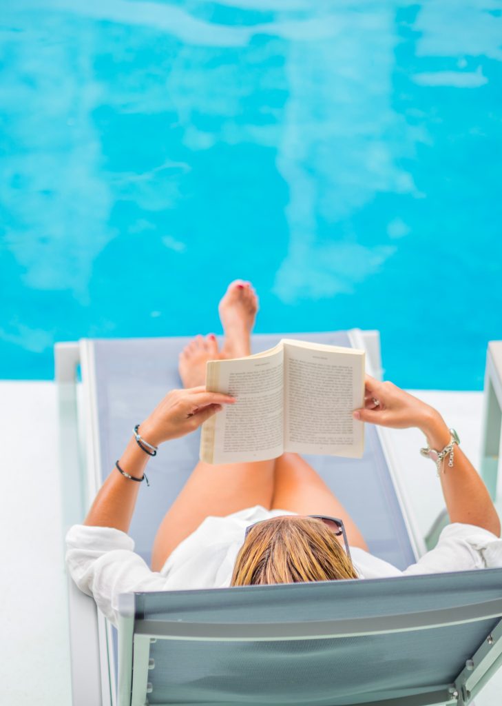 Woman reading a book by the pool.