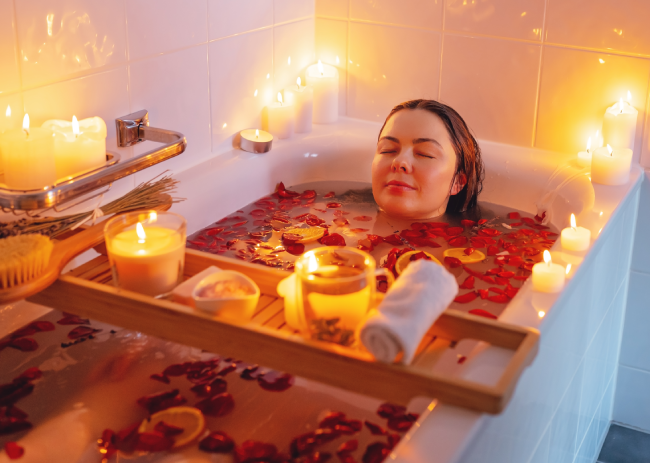 Man relaxing in bathtub with lighted candles arround stock photo